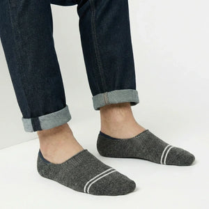 Person wearing dark grey no-show socks with white stripes on a light background