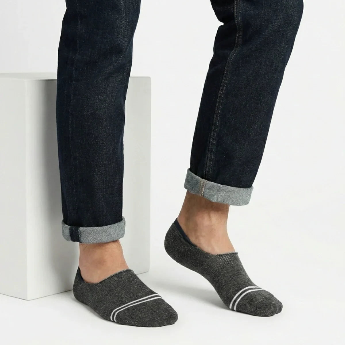 Person wearing dark grey no-show socks with white stripes on a light background