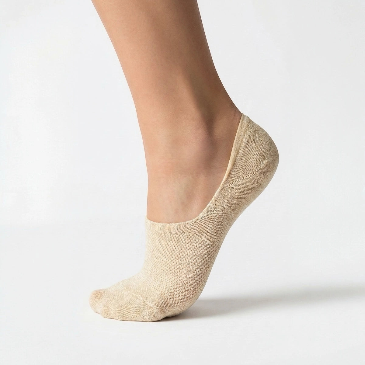 Beige no-show sock with gold sparkly yarn and open weave design for comfort worn by a person on a light grey background