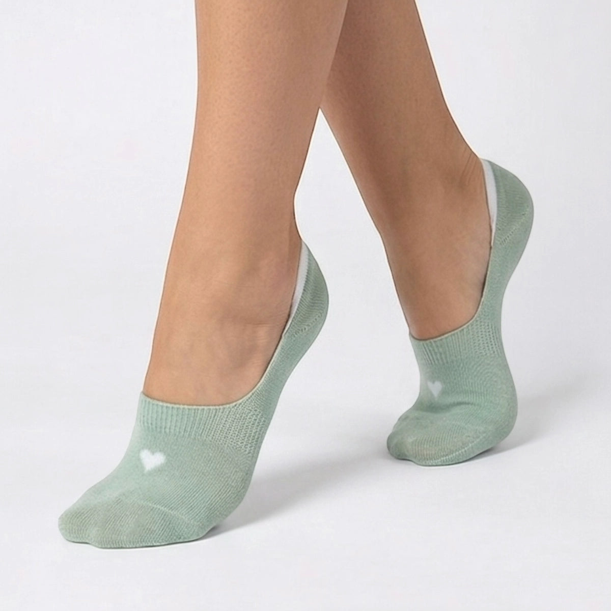 Person wearing a mint no-show sock with a cream heart design on a light grey background