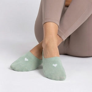 Person wearing a mint no-show sock with a cream heart design on a light grey background
