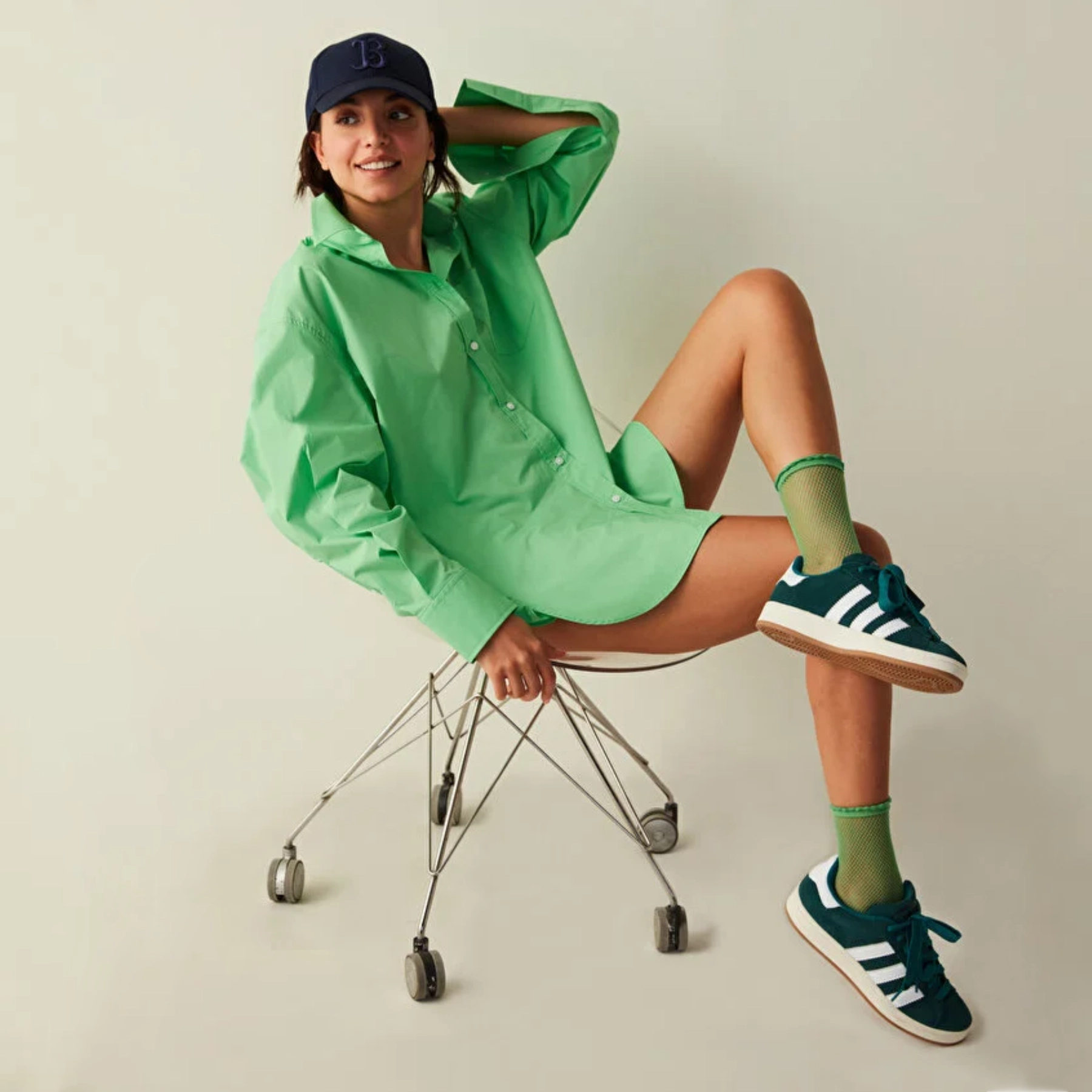 Woman sitting on an office chair wearing a green shirt and quarter length green mesh socks and dark green sneakers