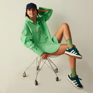 Woman sitting on an office chair wearing a green shirt and quarter length green mesh socks and dark green sneakers