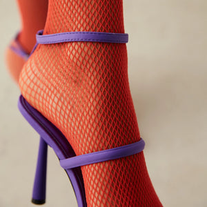 Close-up of woman wearing quarter length orange mesh socks with purple high-heeled strappy shoes