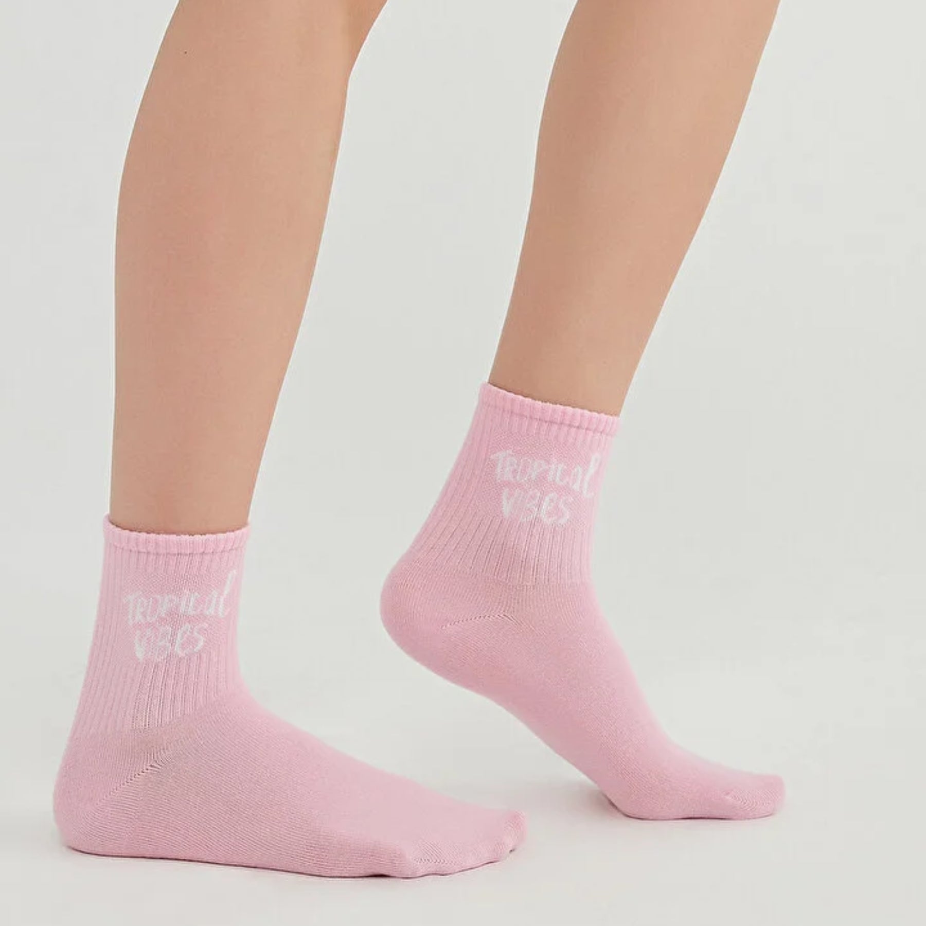 Woman wearing pink quarter length socks with 'Tropical Vibes' slogan