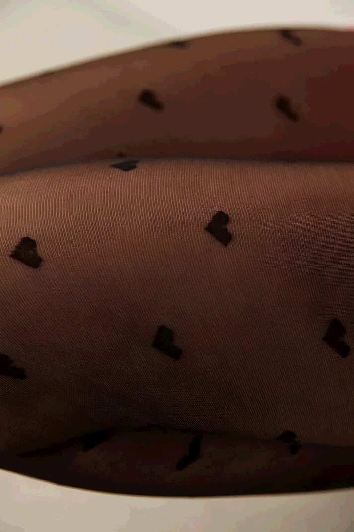Close-up of sheer black tights with a small heart pattern.