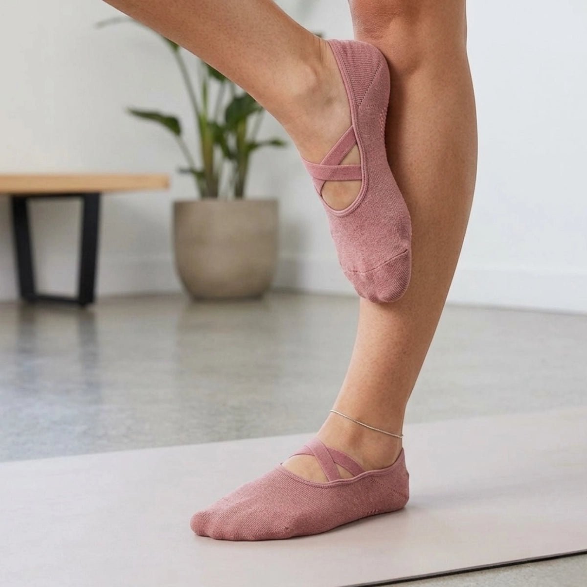 A person wearing rose coloured yoga socks with criss cross band and anti-slip sole