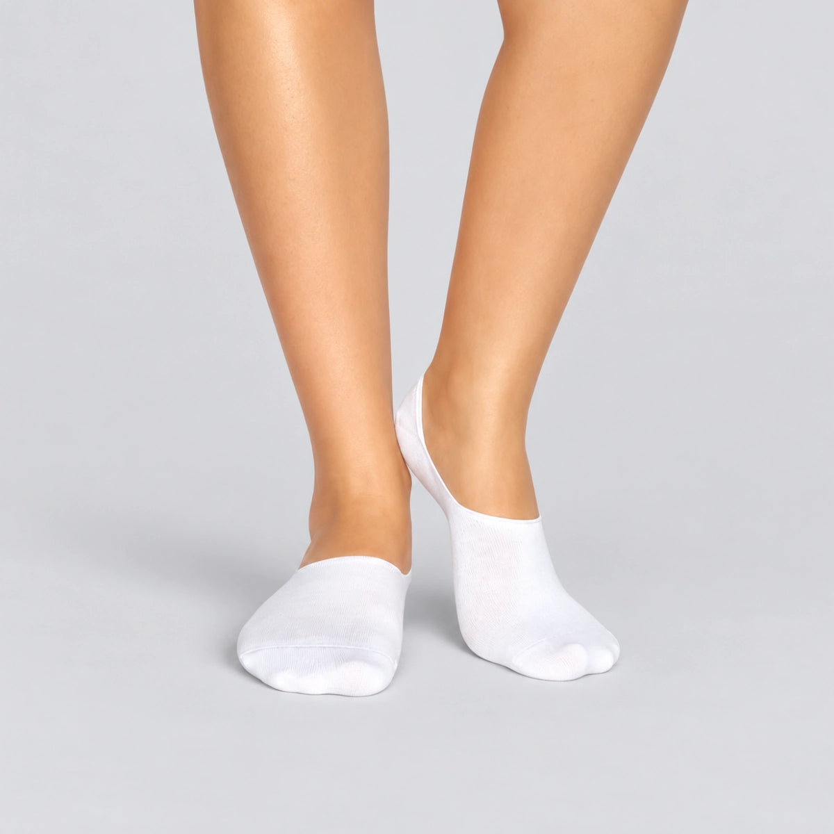 Person wearing seamless white bamboo no-show socks on a white background