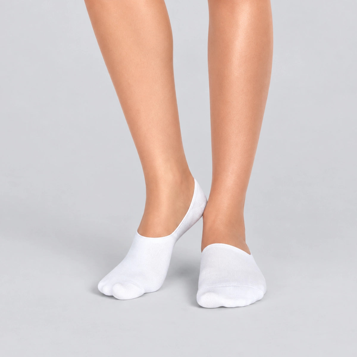 Person wearing seamless white bamboo no-show socks on a white background