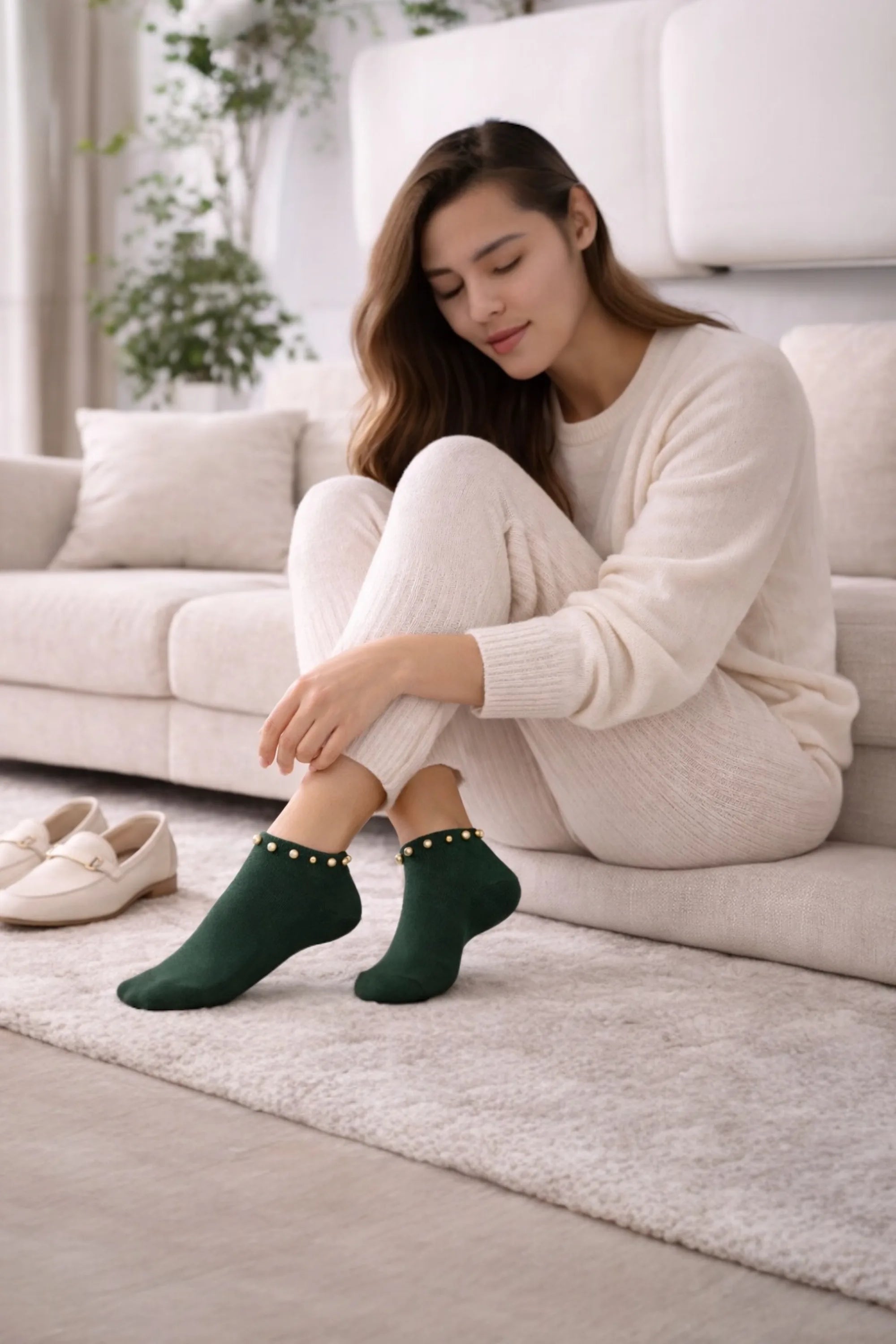 Woman sitting on a couch wearing green socks with a white background