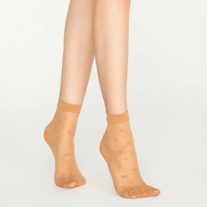 A woman's legs adorned in nude socks featuring a dotted pattern.