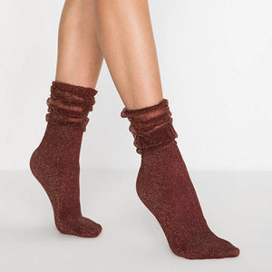 Image of woman's feet wearing burgundy and gold sparkled socks with loose fitting cuff