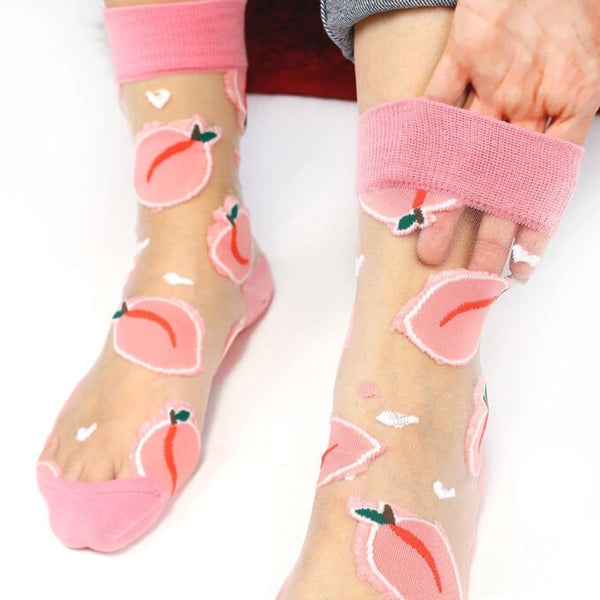 close-up of woman's feet wearing sheer socks with pink fruit and toe, heel and cuff, holding her hand in the sock to show its transparency