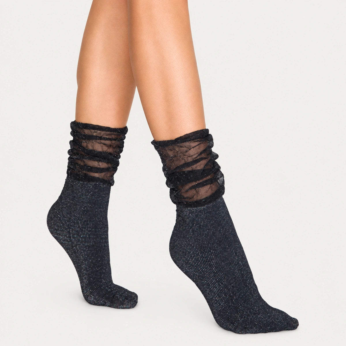 Image of woman's feet wearing black and silver sparkled socks with loose fitting cuff