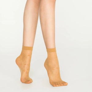 A woman's legs in tan nude socks with a dotted design.