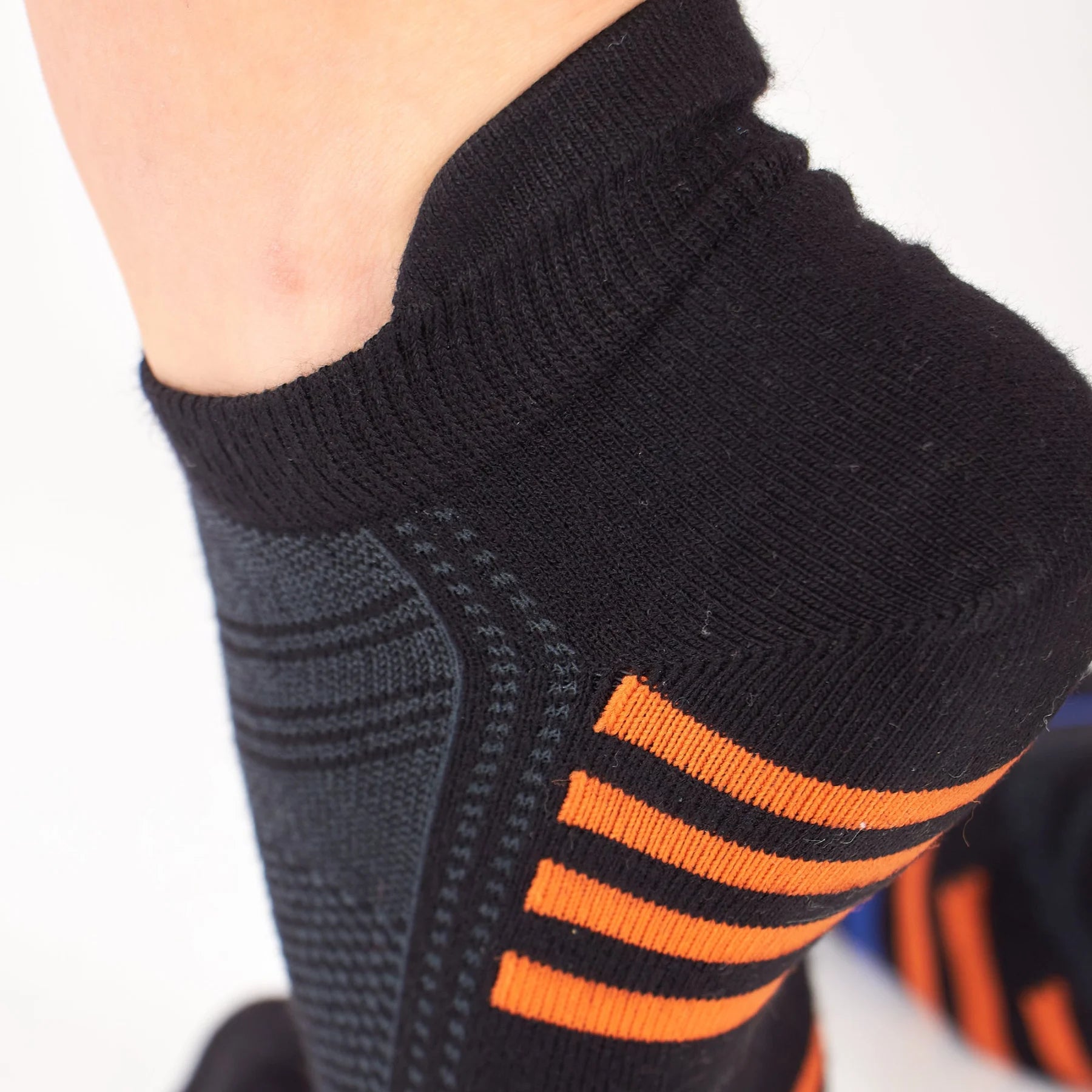 up-close image of woman wearing black bamboo athletic socks with orange and blue stripe