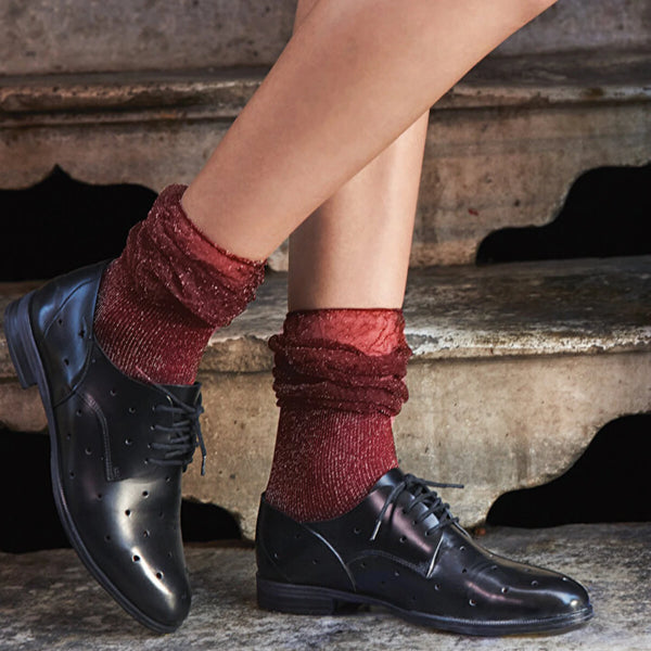 A woman showcases her style with black shoes paired with vibrant red fashion socks.