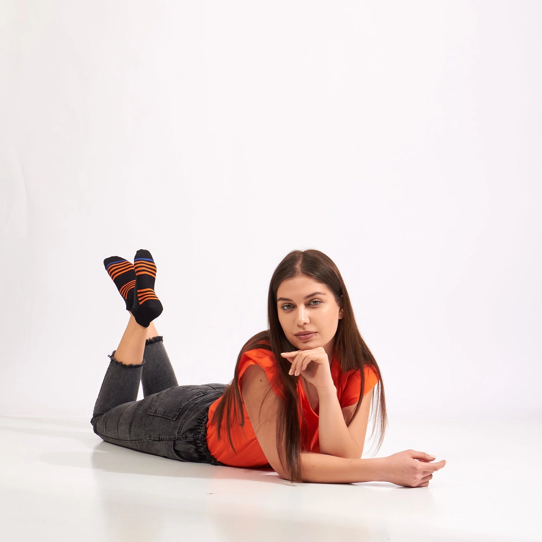woman lying down wearing black bamboo athletic socks with orange and blue stripe