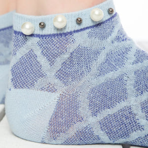 A woman showing a closeup of blue checked ankle socks embellished with pearls around the cuff