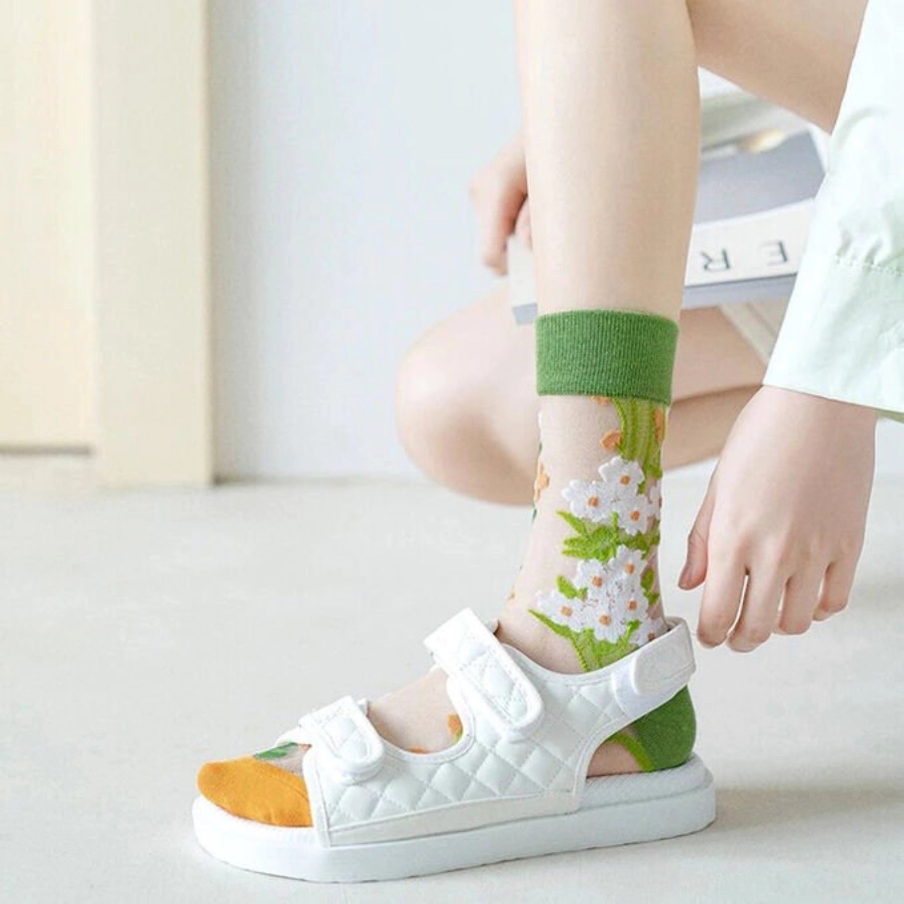 image of person wearing sheer socks with plant detail in a white sandal