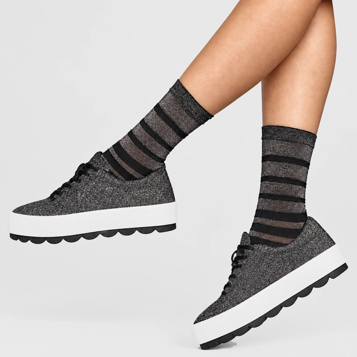 person wearing black and silver striped crew socks wearing stylish sneakers