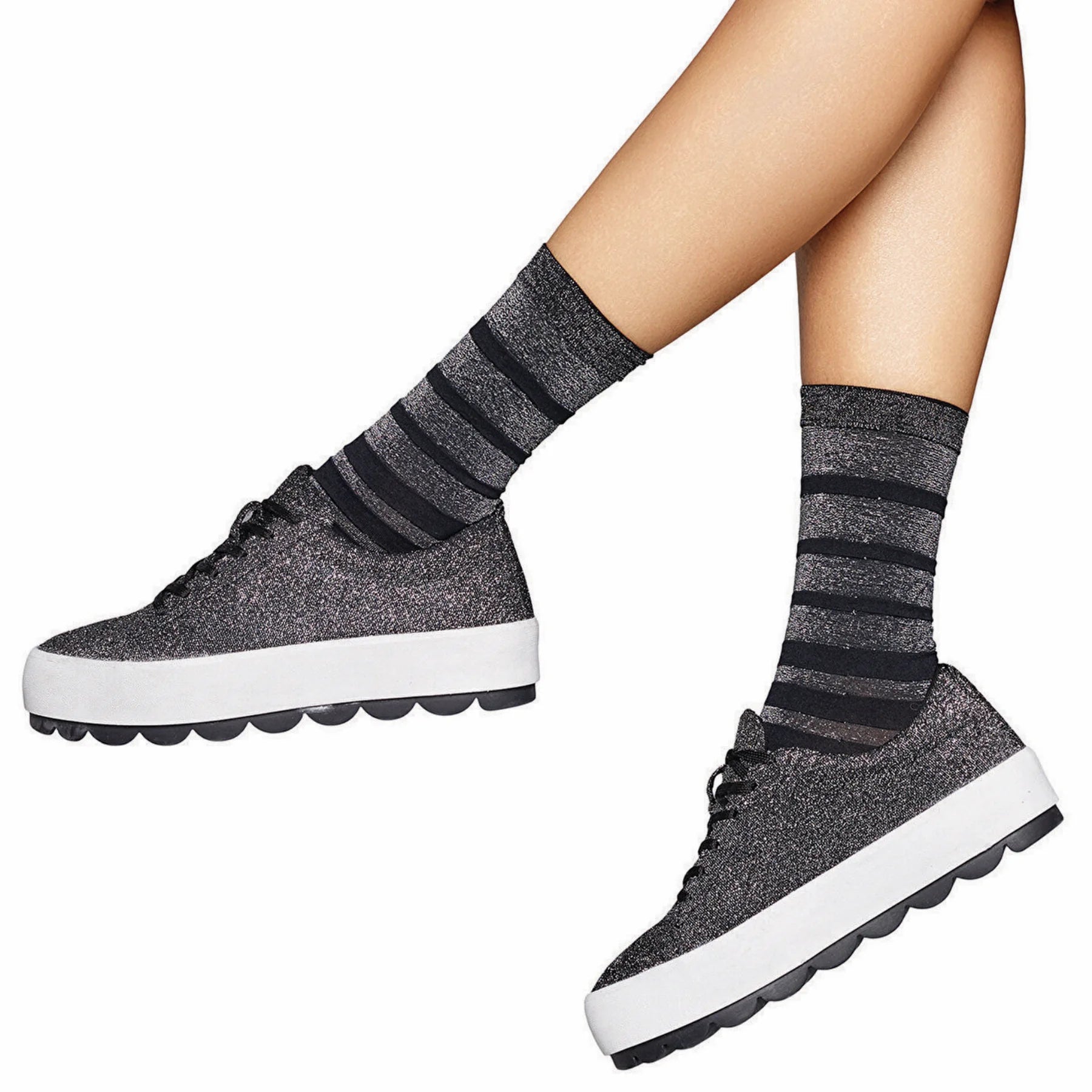 person wearing black and silver striped crew socks wearing stylish sneakers