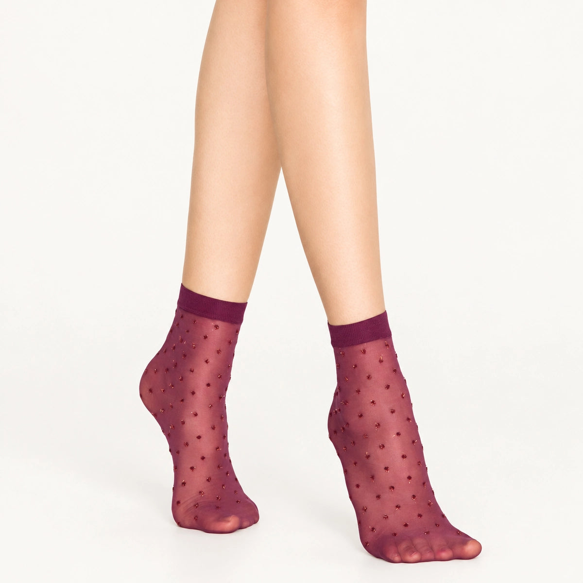 Woman wearing sheer amethyst ankle socks with gold dots on white background
