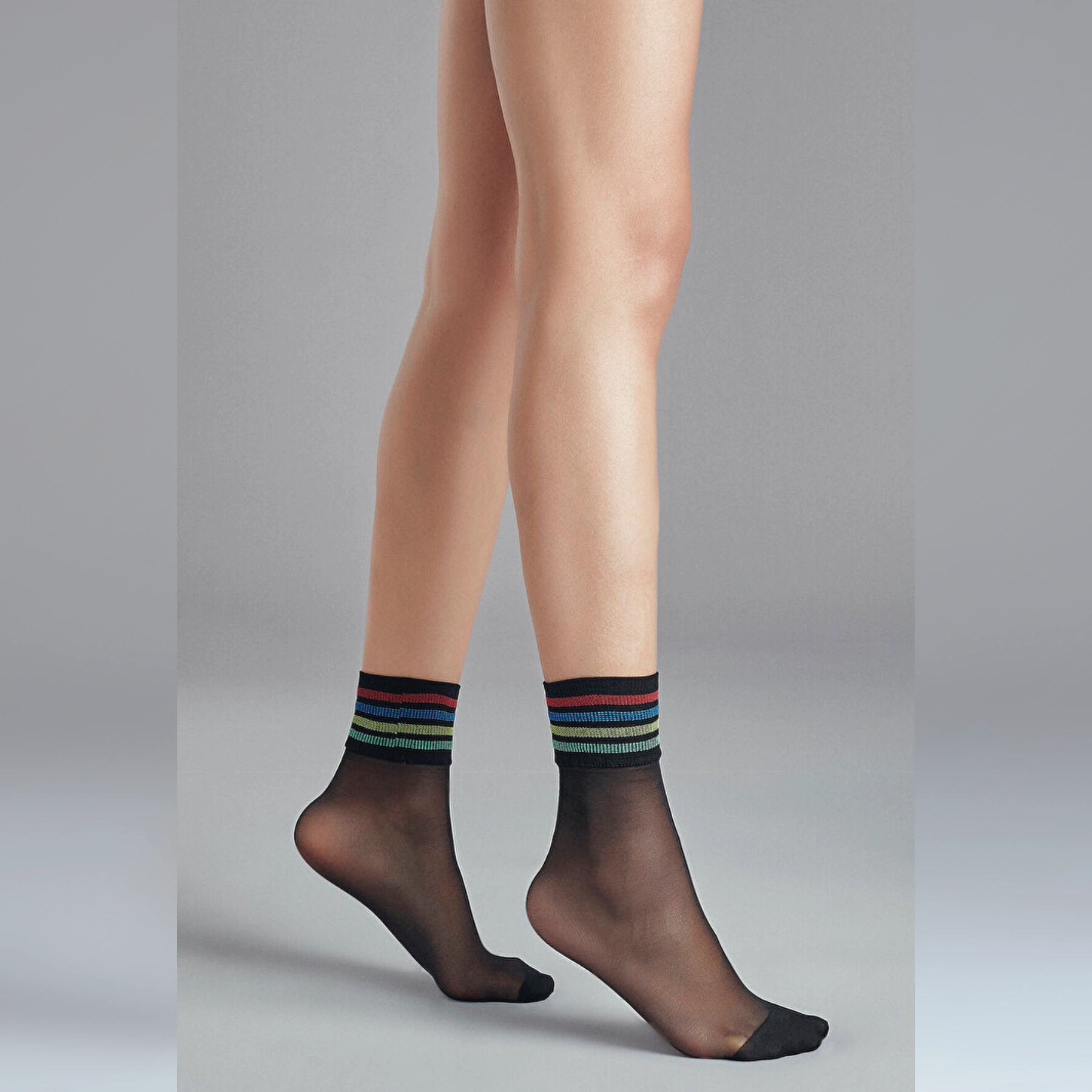 person wearing sheer black crew socks with multicoloured striped cuff