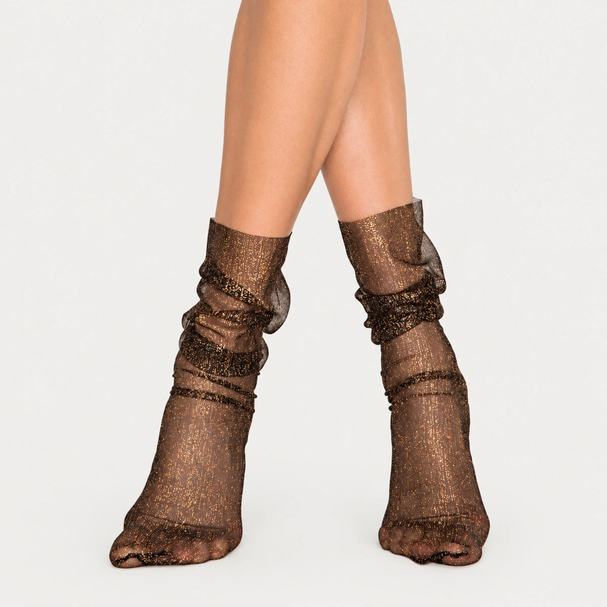 Women's black sheer mesh ankle socks with glittering gold shimmer and a loose, ruched fit on model's legs.